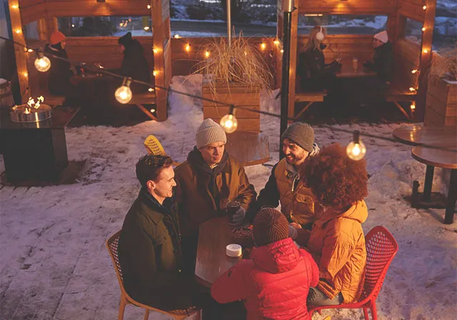 Group of friends sits at an outdoor table at a brewery during winter