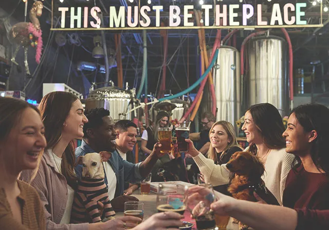 group of friends cheers pint glasses inside Cold Garden's taproom