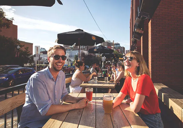 couple sitting on the patio of National 17 enjoying pints of beer on a summer day