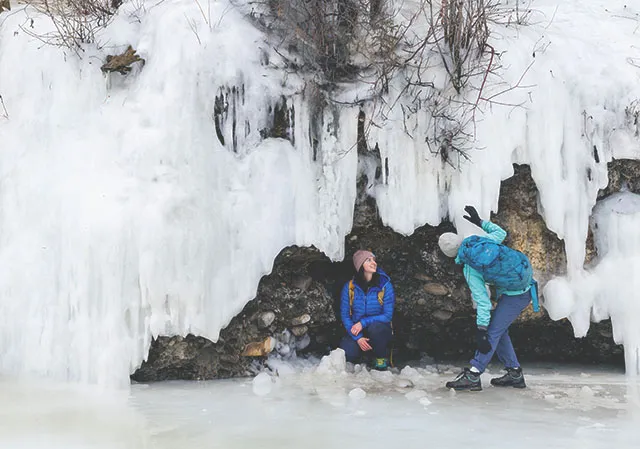 two ladies explore ice formations during winter in Fish Creek Provincial Park