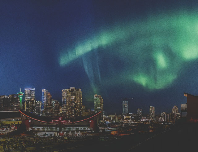 The Northern Lights shine brightly above downtown Calgary at night