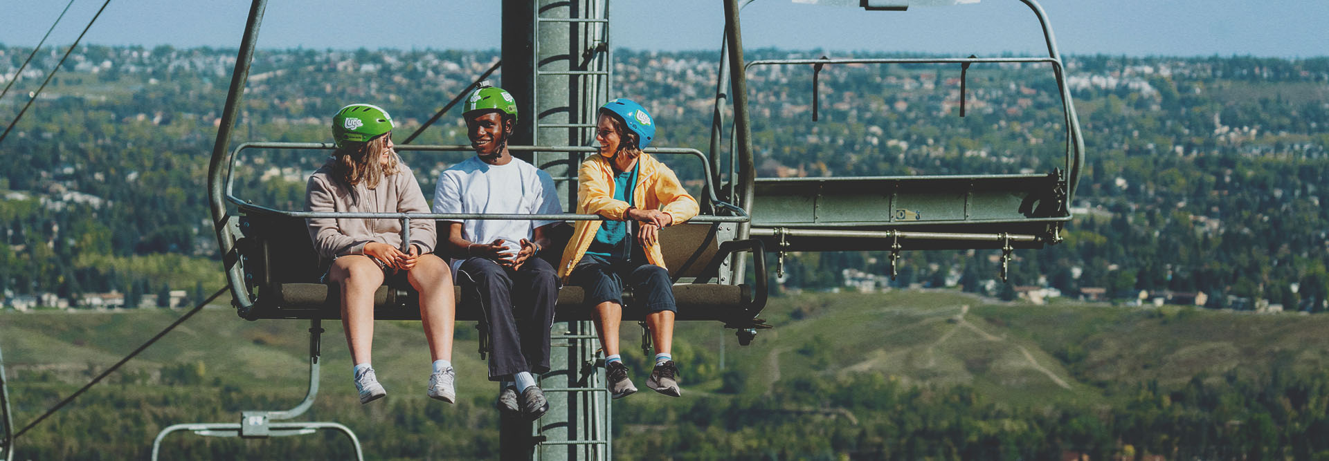 friends riding the WinSport chairlift up to Downhill Karting