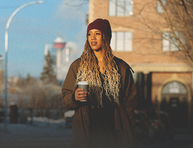 Woman walking past Livery Shop in Inglewood with coffee