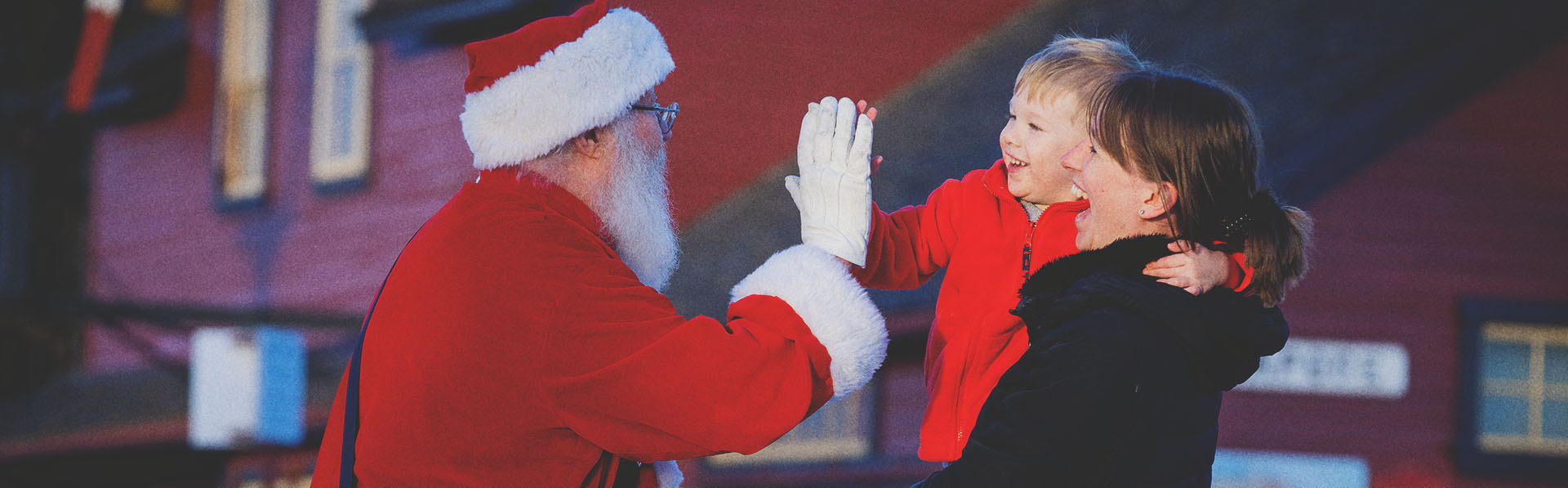 Santa is giving a high five to a little boy at Heritage Park Calgary