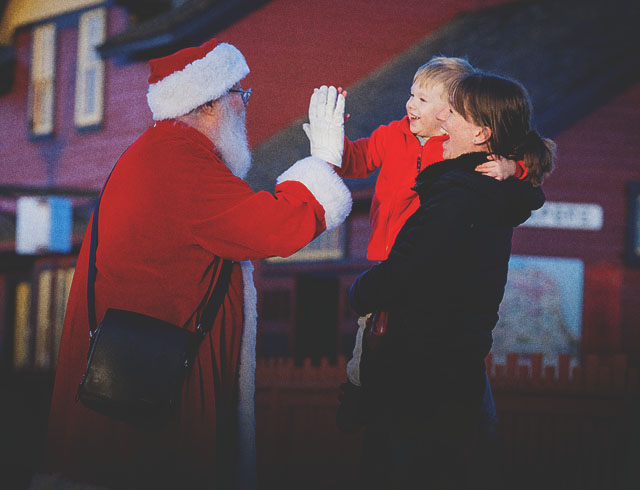 Santa is giving a high five to a little boy at Heritage Park Calgary