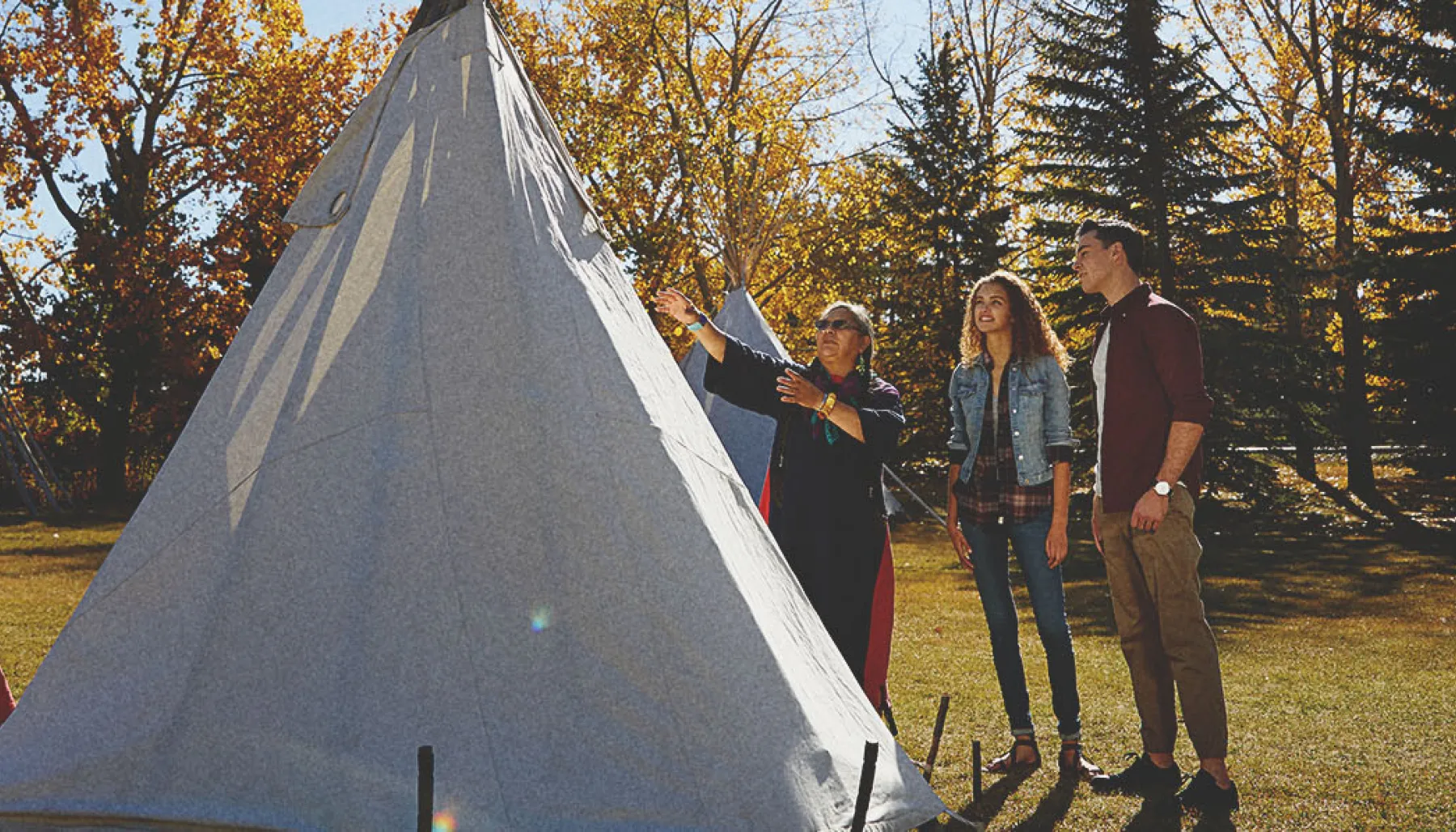 People learning how to set up a tipi at Heritage Park