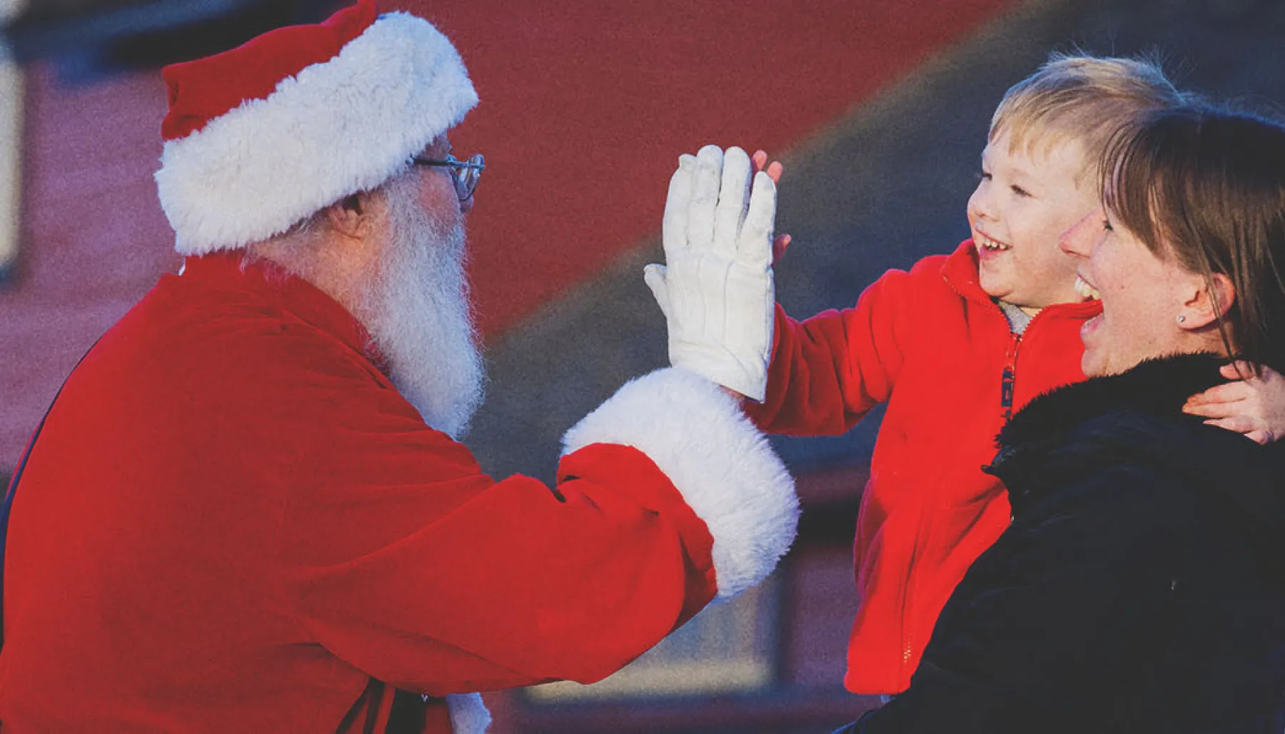 Santa is giving a high five to a little boy at Heritage Park Calgary