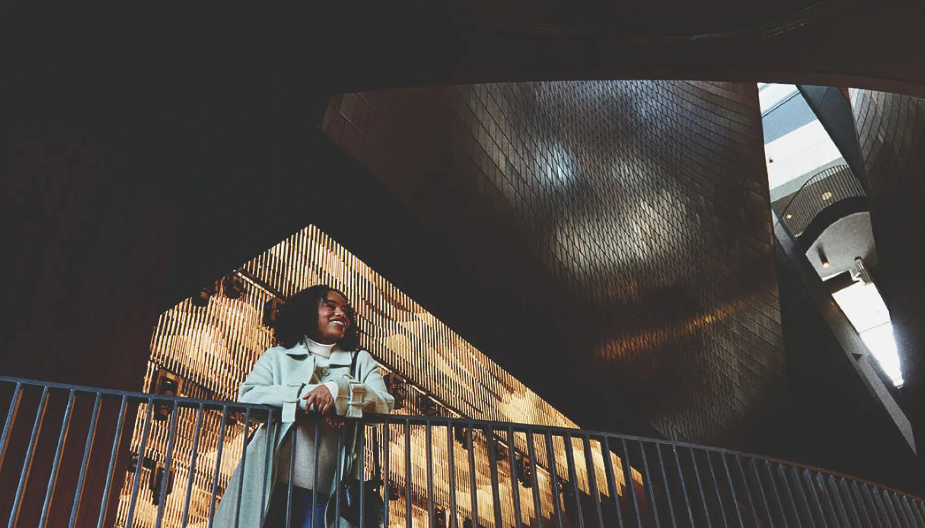 a woman standing inside Studio Bell building and surrounded by its modern architecture