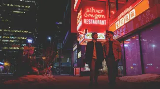 couple walking through Calgary's Chinatown at night with the illuminated Silver Dragon restaurant sign behind them