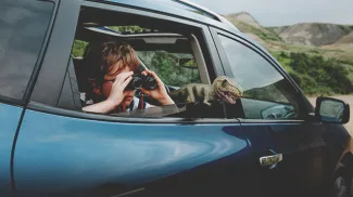 child looking through binoculars in the backseat of a vehicle