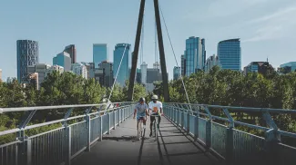 Friends biking over the Bow River pathway bridge