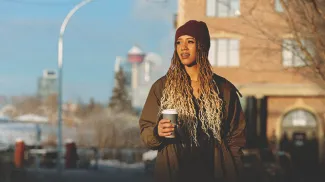 Woman walking past Livery Shop in Inglewood with coffee