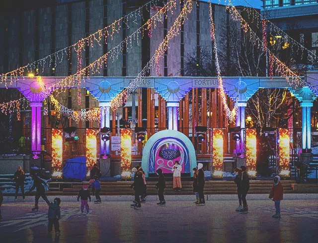 People are ice skating at Olympic Plaza skating rink