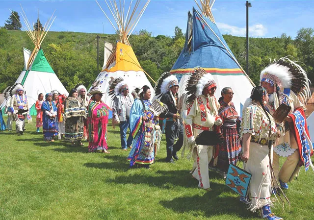 People wearing traditional Indigenous clothing at Elbow River Camp during the Calgary Stampede