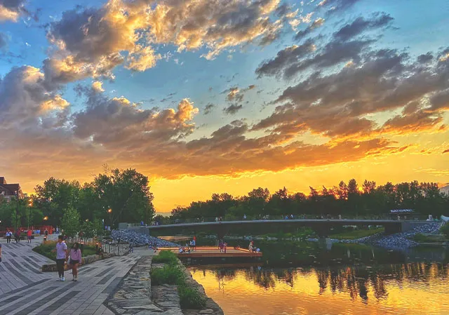 people walking throughout Eau Claire plaza in Calgary during a beautiful summer sunset