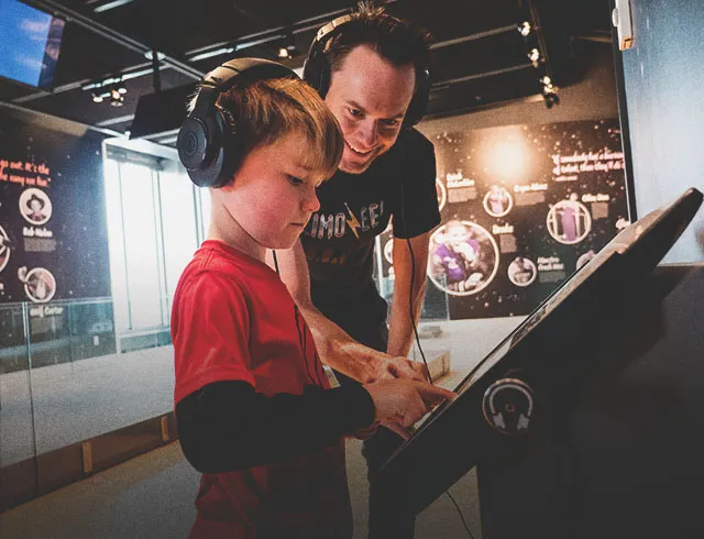 father and son exploring displays at Studio Bell