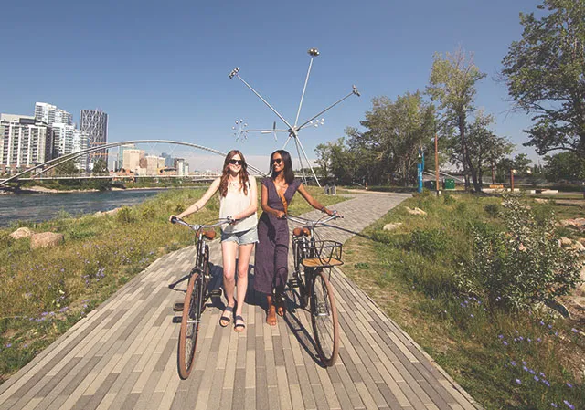 two ladies walk their bikes along a pathway on St. Patrick's Island Park