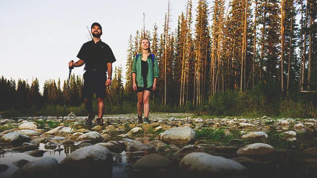 two people hiking through a creek in Fish Creek Provincial Park