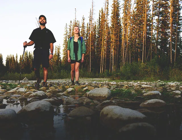 two people hiking through a creek in Fish Creek Provincial Park