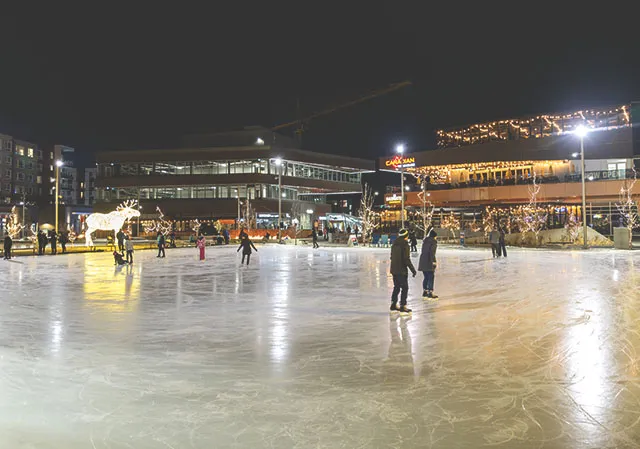 people outdoor ice skating at Central Commons Park in University District at night
