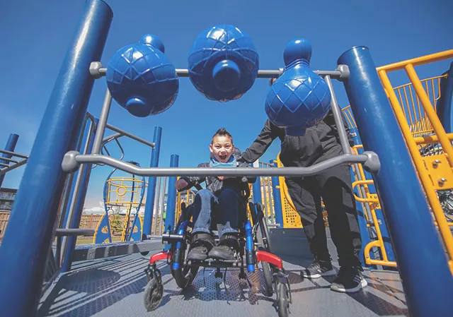 young boy in a wheelchair plays on the accessibly playground at University District