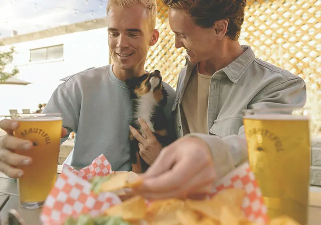 couple drinking beer at Ol Beautiful Brewing Co on the patio with their dog