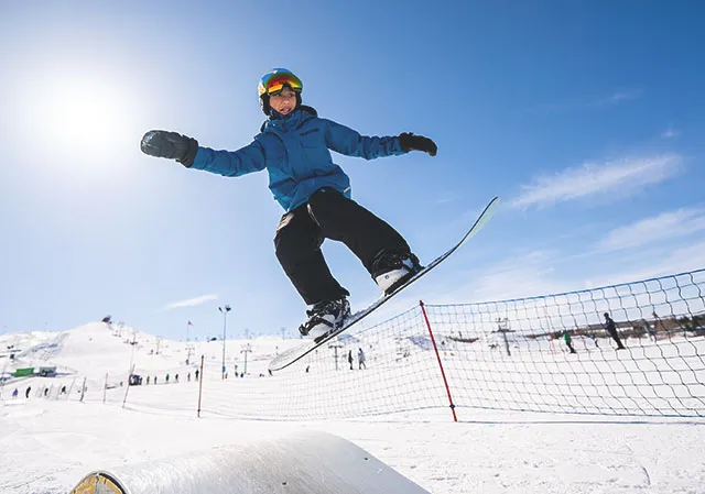 child taking a snowboard jump at WinSport