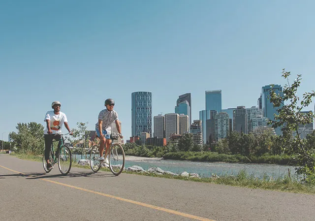 couple biking along the Bow River Pathway near downtown Calgary