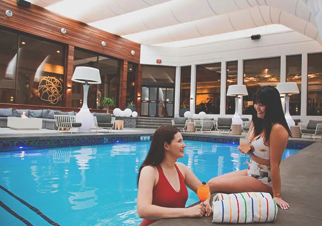 ladies enjoy a cocktail by the pool at Hotel arts Poolside