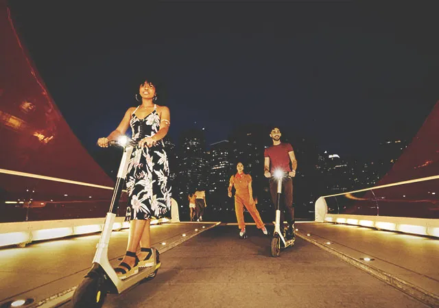 A group of people riding e-scooters on the Peace bridge