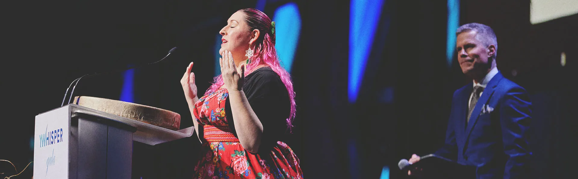 a woman speaking at a podium on stage at Calgary TELUS Convention Centre