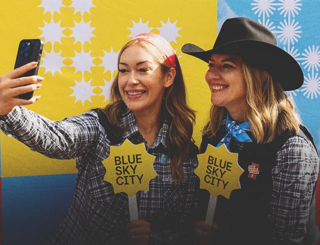 two people are taking a selfie with blue sky city photo prop