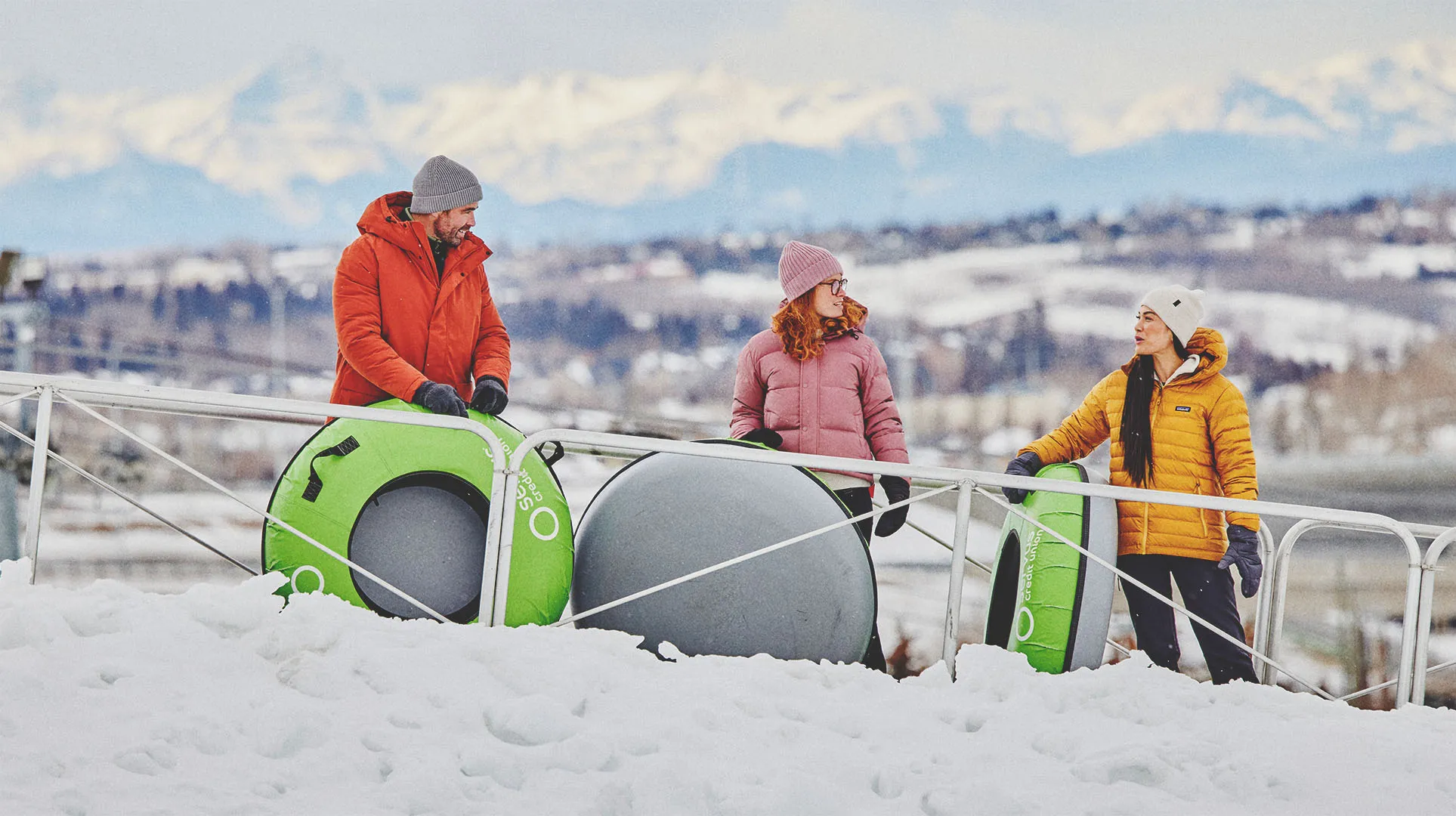 three people tubing on a snowy hill at Winsport Calgary